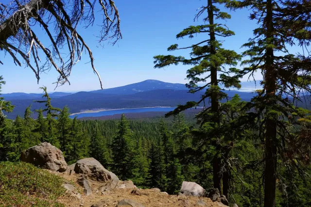 Sky Lakes Wilderness: a lake and forested ridges from a rocky viewpoint above the trail